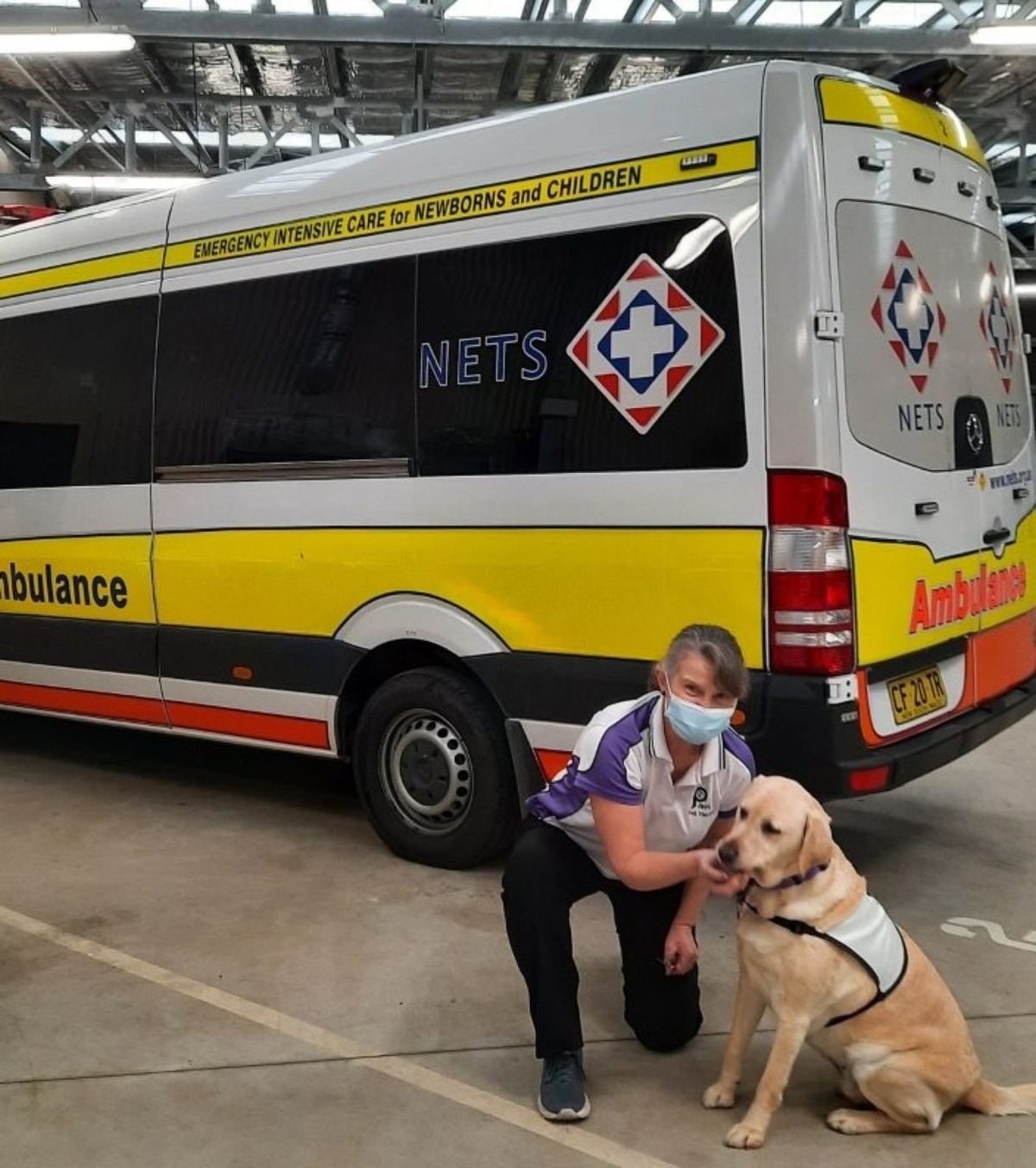 A PAWS volunteer and his dog beside an ambulance