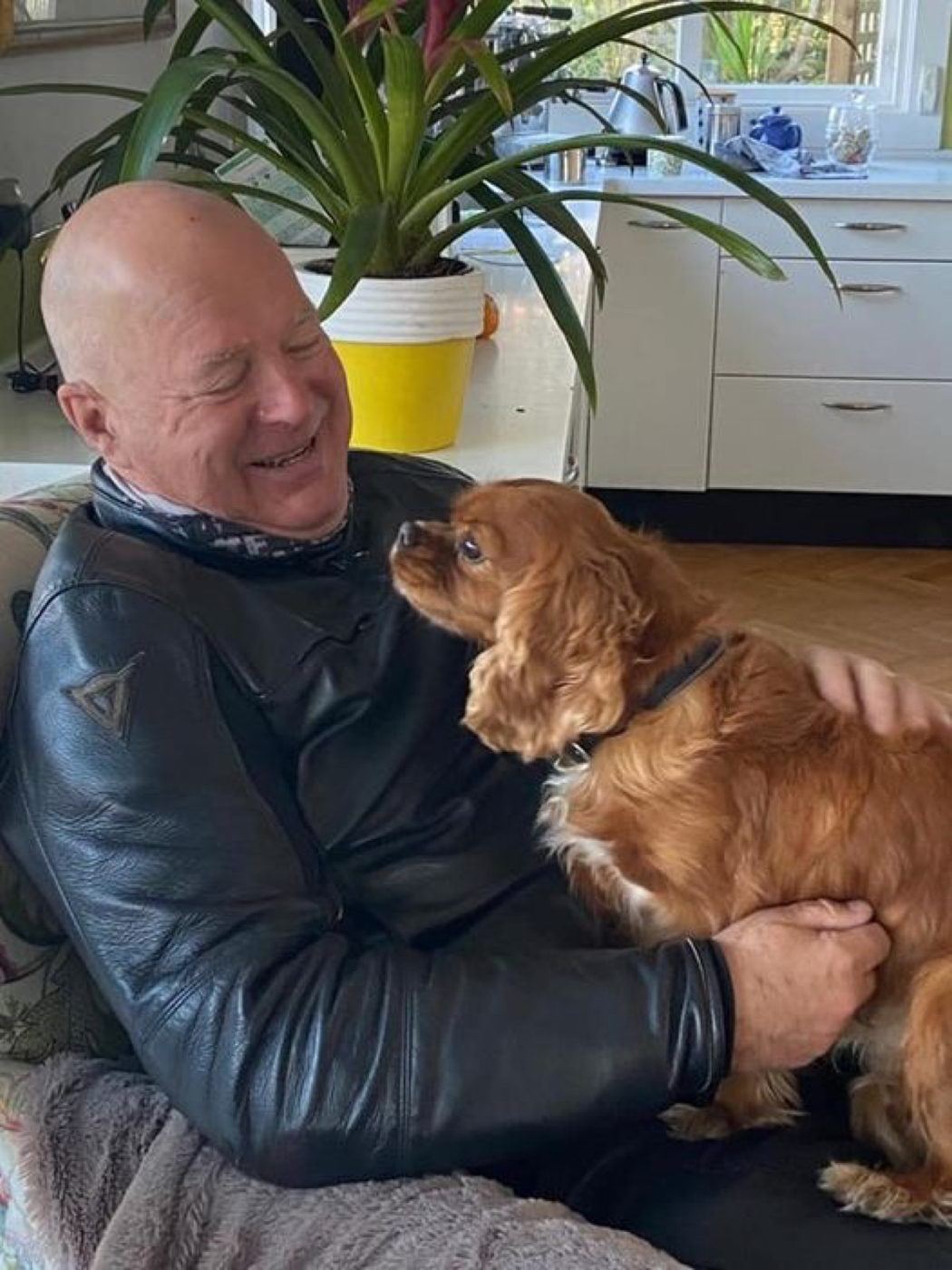 A smiling man cuddling his spaniel