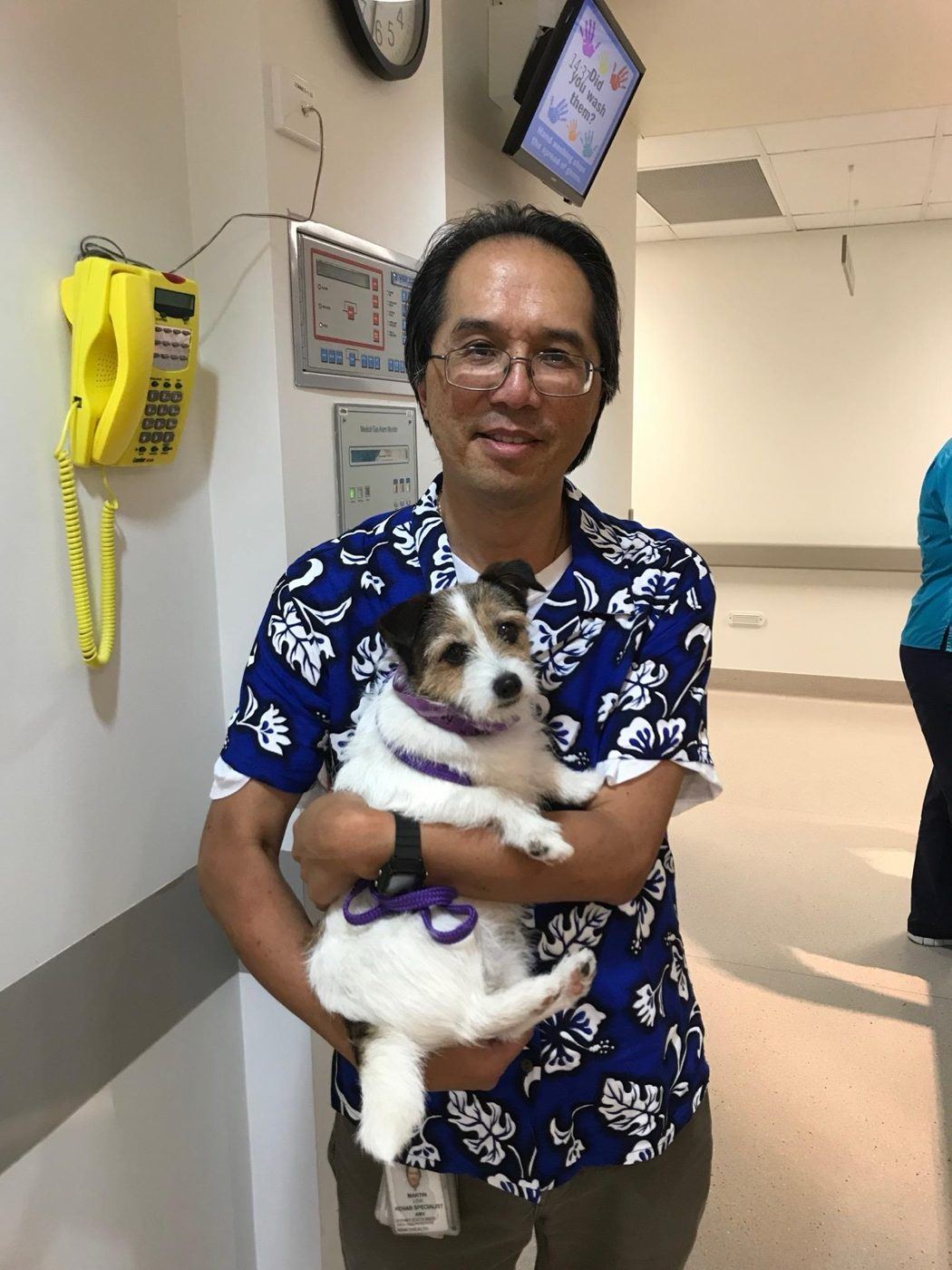 A smiling man holding a small PAWS dog