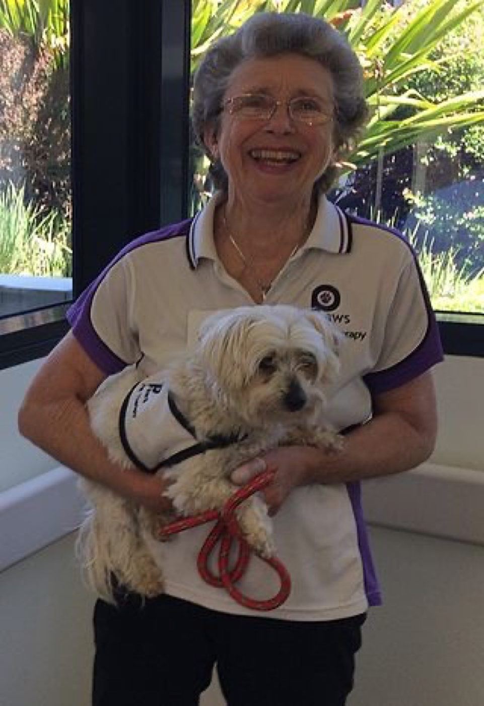 A volunteer hugging her small white dog