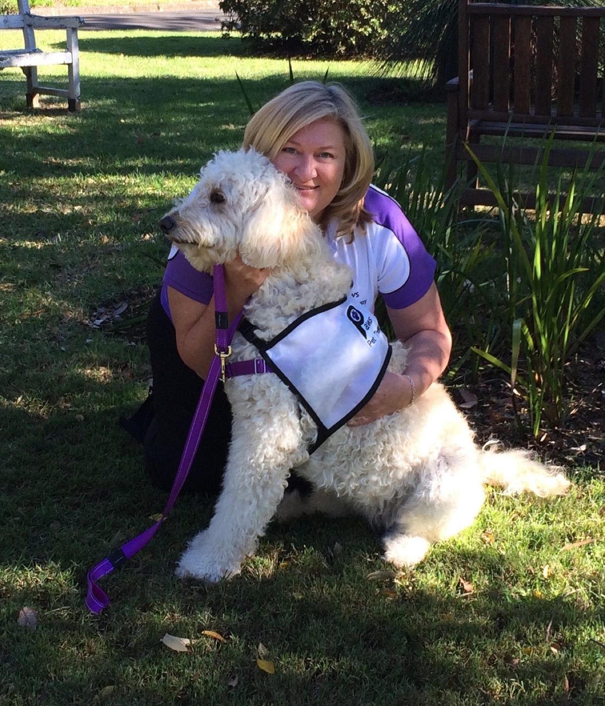 A volunteer hugging her white fluffy dog in the garden