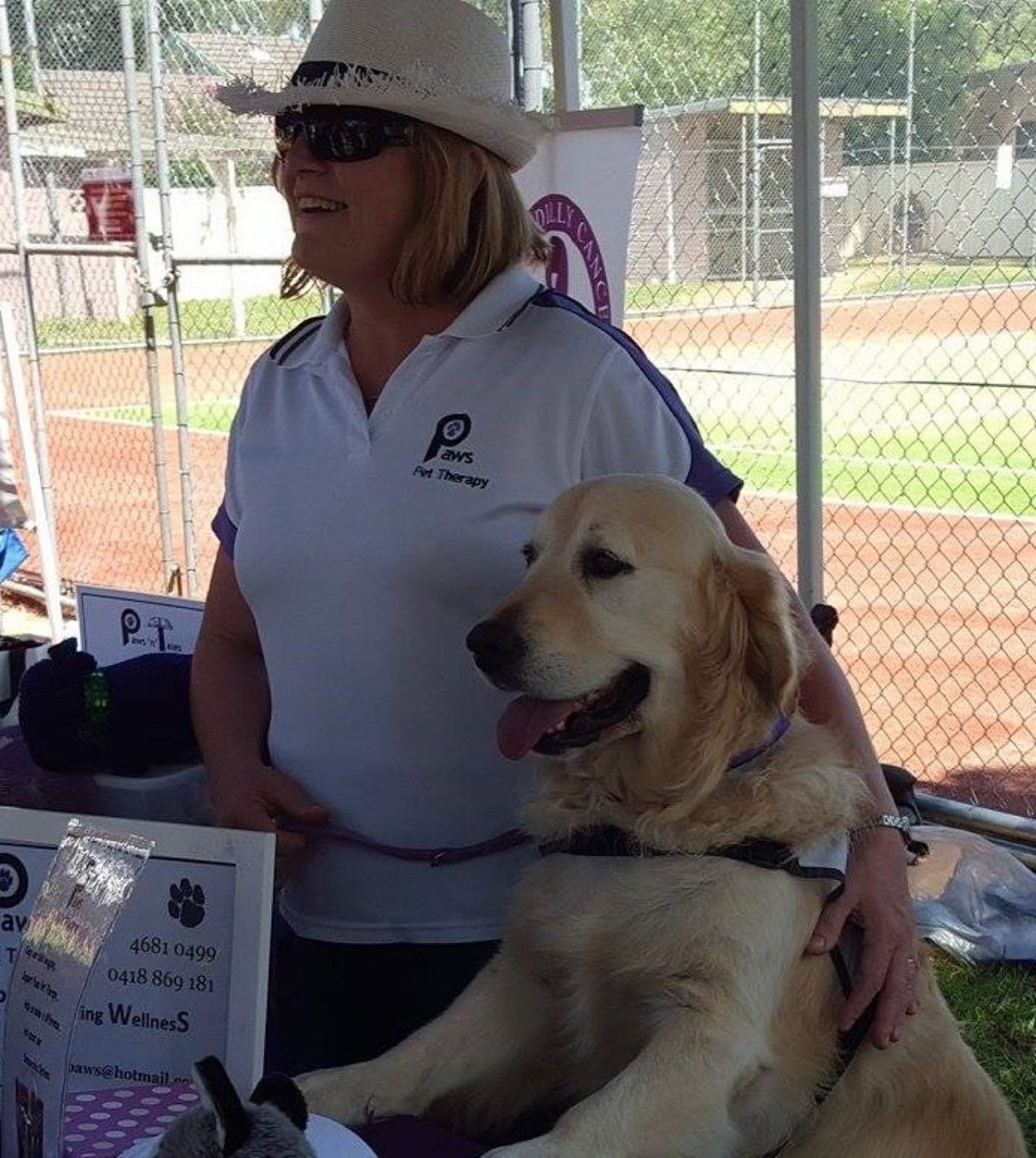 A volunteer in a hat with her golden retriever