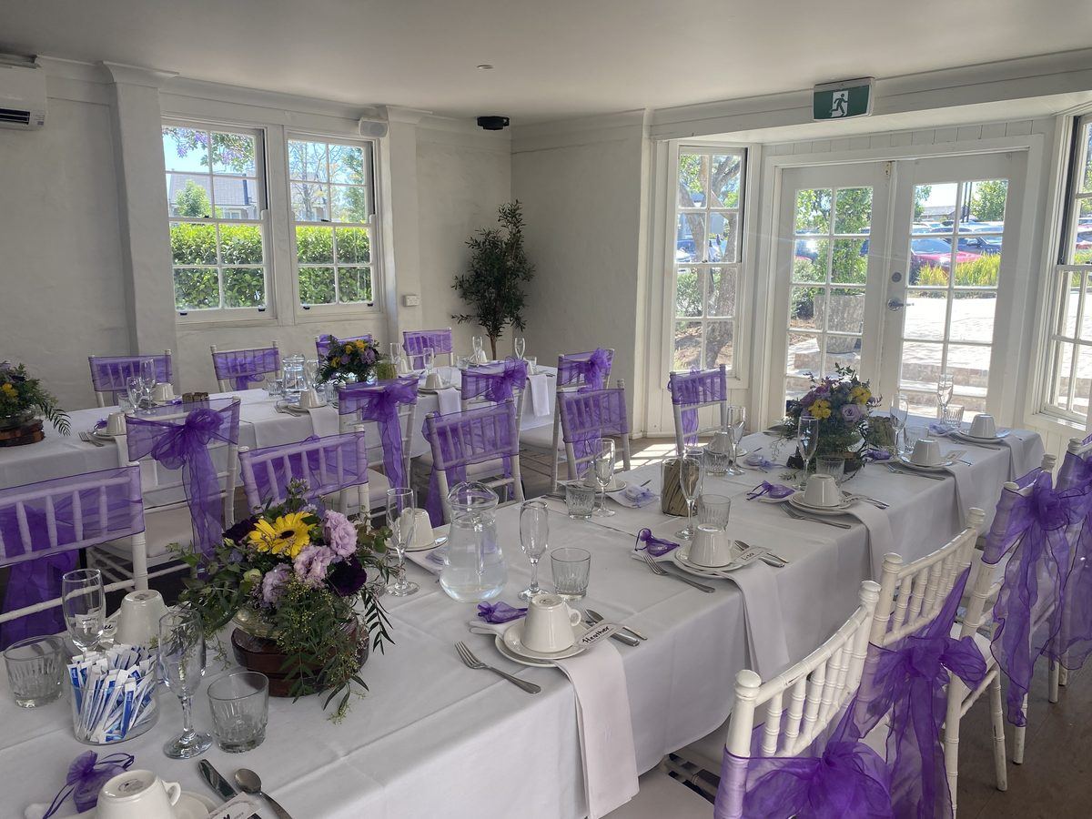 A long lunch table set with purple sashes