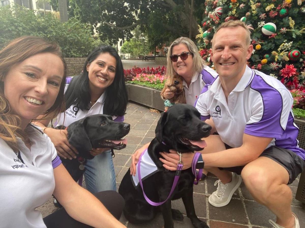 Three PAWS volunteers and their dog at a community event