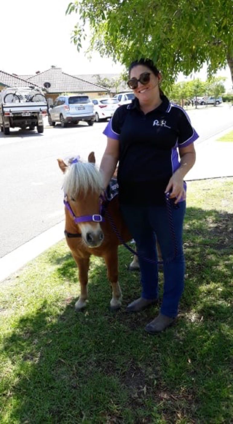 A PAWS'n'Hooves volunteer standing with a pony on a lead