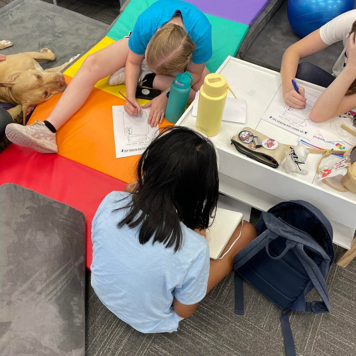 Children reading on the floor beside a PAWS dog