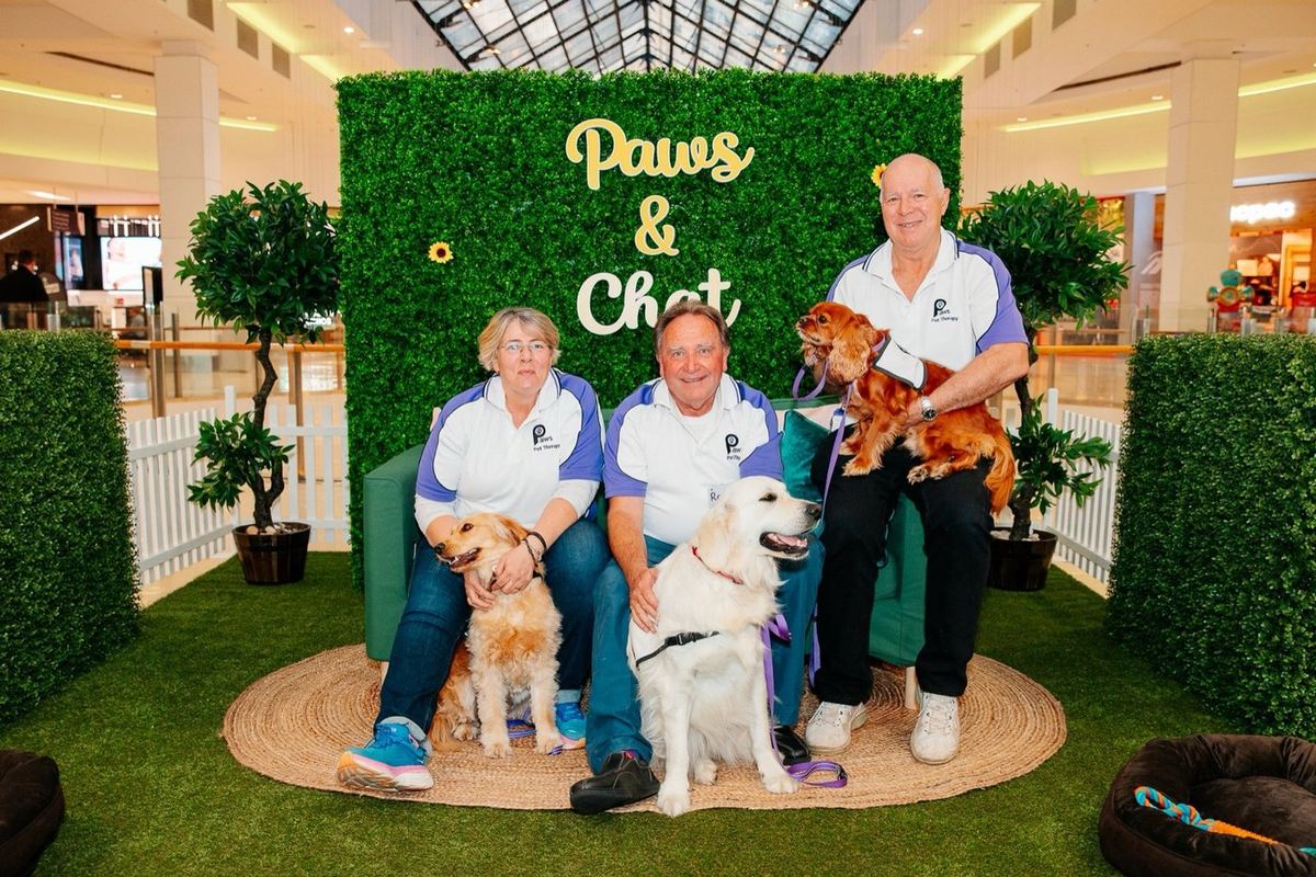 A family posing with a PAWS therapy dog at an event photo backdrop