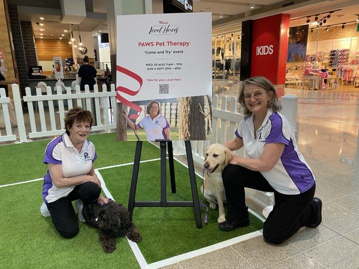 A PAWS team at an event with a sign