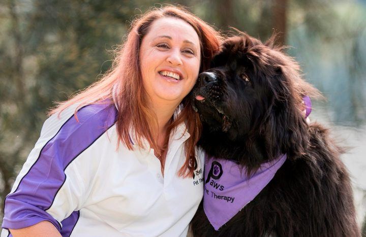 A volunteer cuddling her big black dog