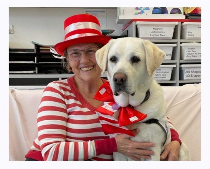 A volunteer in a Cat in the Hat costume with her labrador