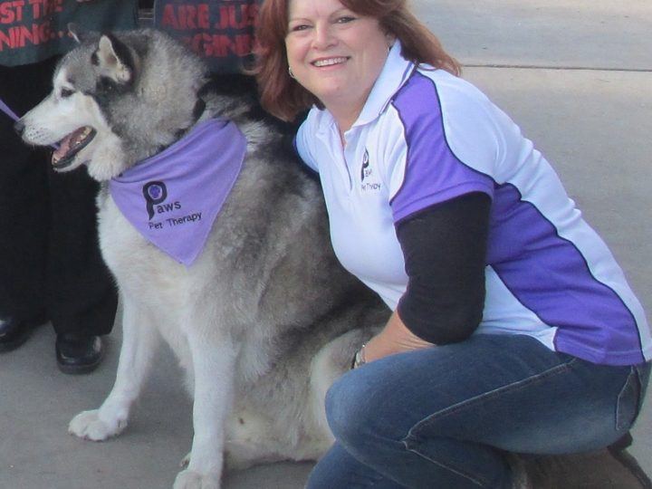 A volunteer kneeling with her husky