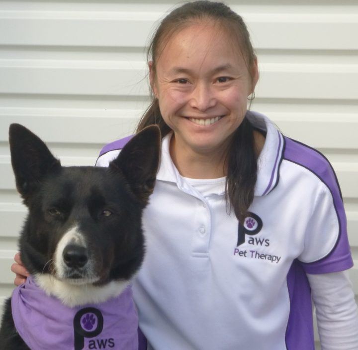 A volunteer smiling beside her corgi-cross