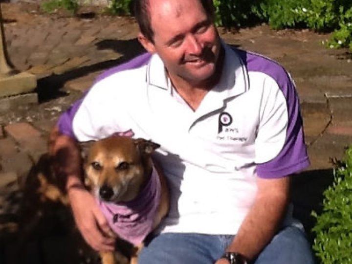 A volunteer smiling with his small dog