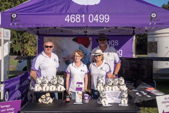 PAWS volunteers at their stall under a purple tent