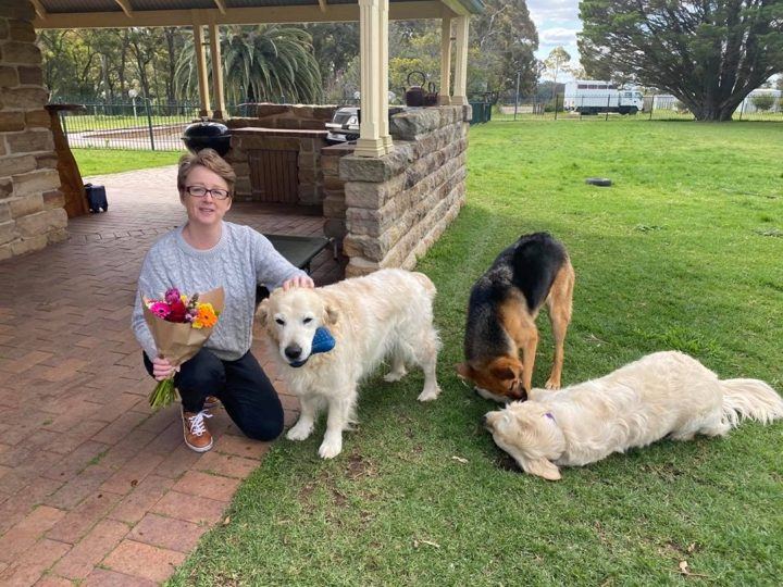 PAWS volunteers relaxing with their dogs on the grass