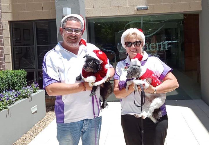 Two volunteers holding their small dogs at a celebration