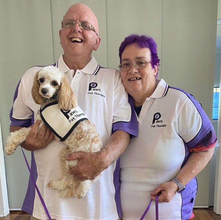 Two volunteers holding their small dogs