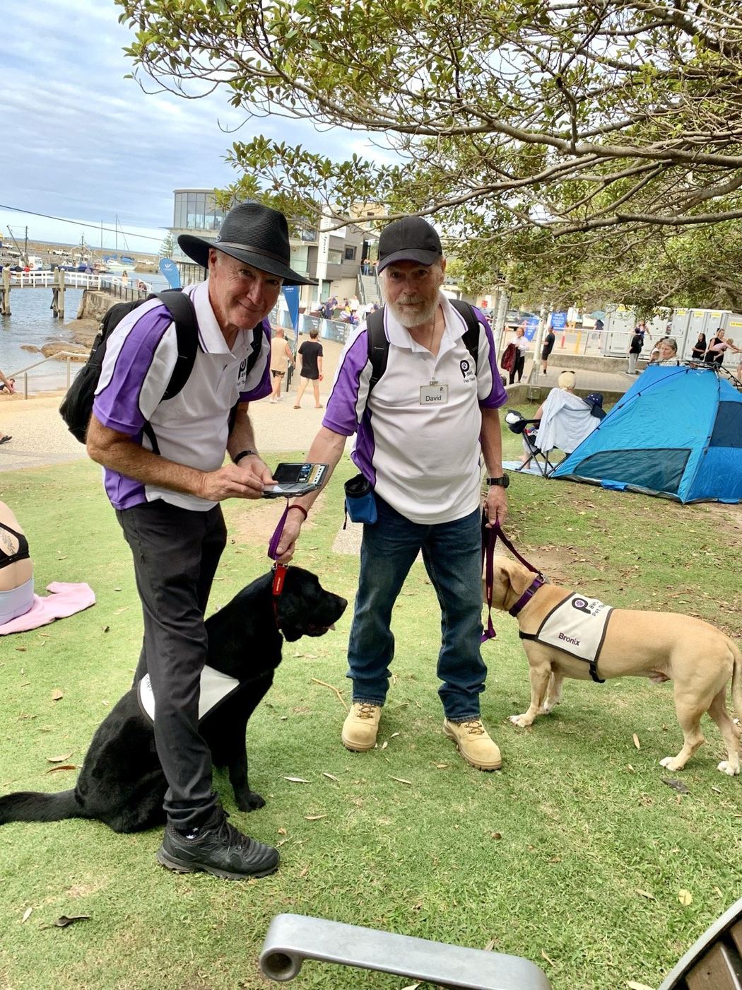 Two PAWS volunteers with their therapy dogs at a community outing
